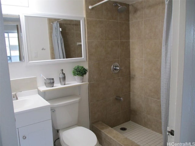 bathroom with a tile shower, vanity, and toilet