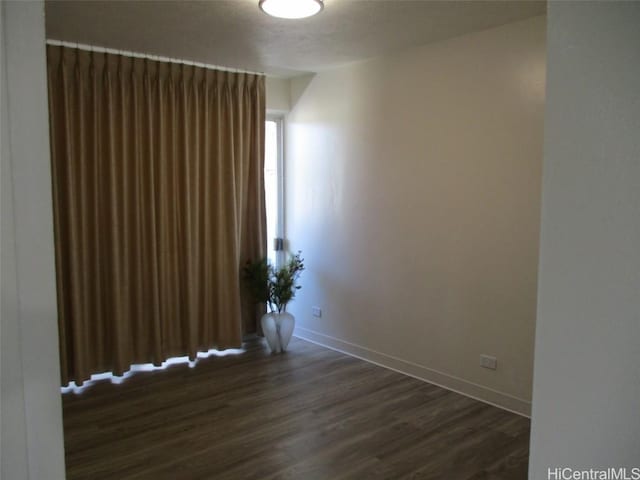 empty room with dark wood-style floors and baseboards