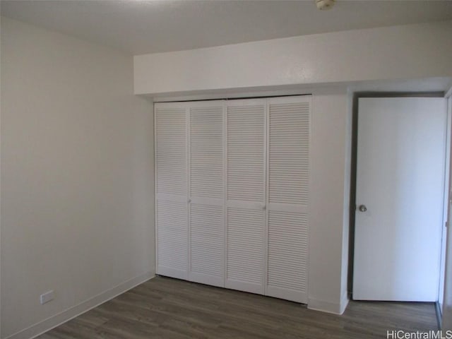 unfurnished bedroom with a closet, baseboards, and wood finished floors