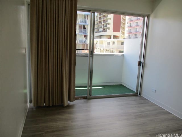 doorway to outside featuring a view of city, wood finished floors, and baseboards