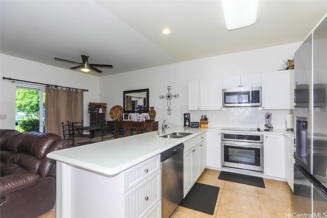 kitchen featuring light tile patterned floors, stainless steel appliances, a peninsula, a sink, and open floor plan