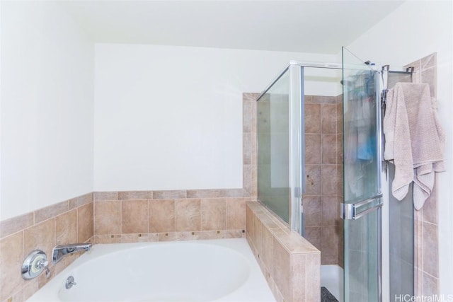 bathroom featuring a garden tub and a shower stall