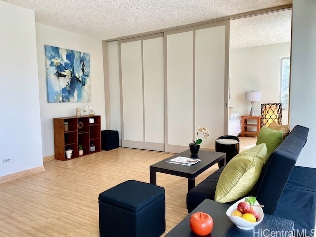 living area with a textured ceiling, baseboards, and wood finished floors