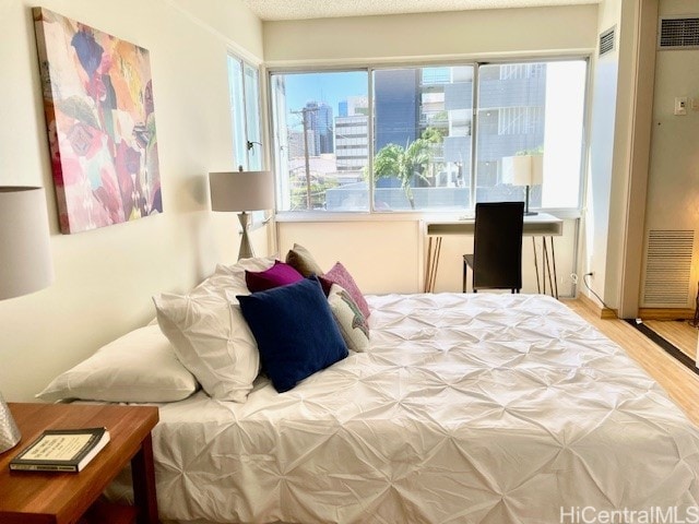 bedroom featuring a view of city, wood finished floors, and visible vents