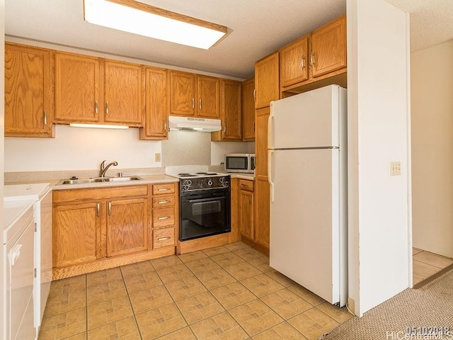 kitchen featuring washer and clothes dryer, freestanding refrigerator, black / electric stove, under cabinet range hood, and a sink