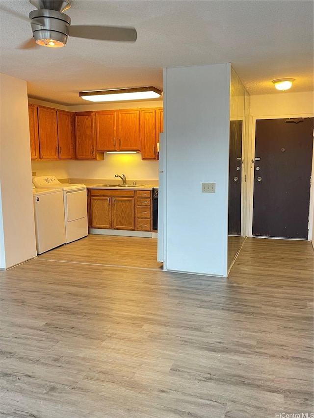 1710 Punahou St Unit 305, Honolulu, HI 96822 - kitchen featuring washer and clothes dryer, a sink, light wood-style flooring, brown cabinetry, and light countertops