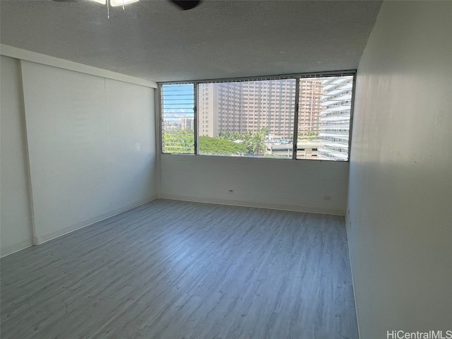 empty room with a textured ceiling, a city view, and wood finished floors