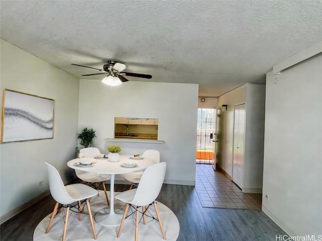 dining room featuring baseboards, a textured ceiling, a ceiling fan, and wood finished floors