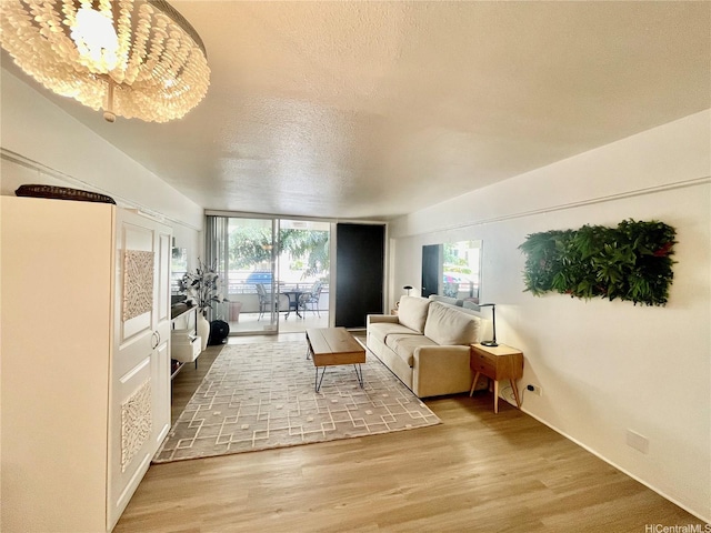 living area featuring plenty of natural light, a textured ceiling, wood finished floors, and a notable chandelier