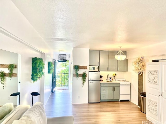 kitchen featuring white appliances, gray cabinets, light wood-style floors, a textured ceiling, and open floor plan