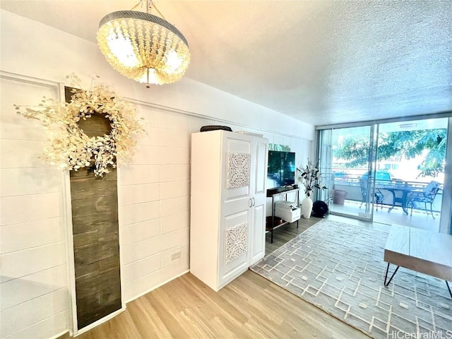 living room with a wall of windows, light wood-style floors, and a textured ceiling