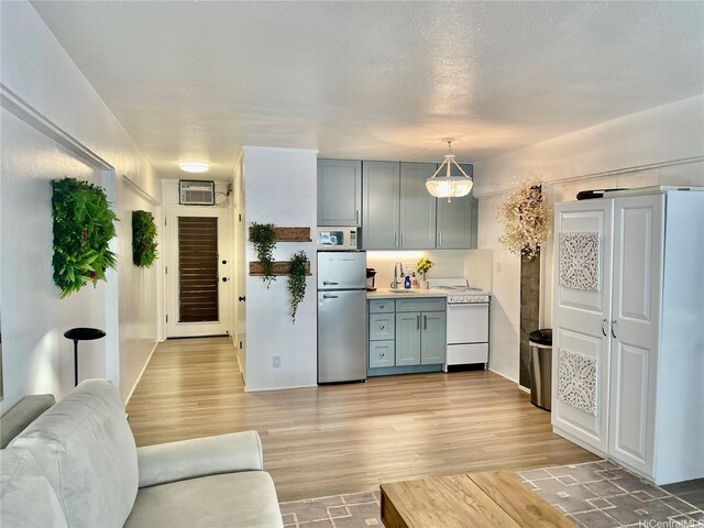 kitchen featuring white appliances, light wood-style floors, light countertops, gray cabinets, and a wall unit AC