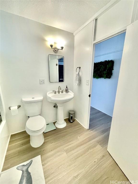 bathroom featuring baseboards, toilet, wood finished floors, and a textured ceiling