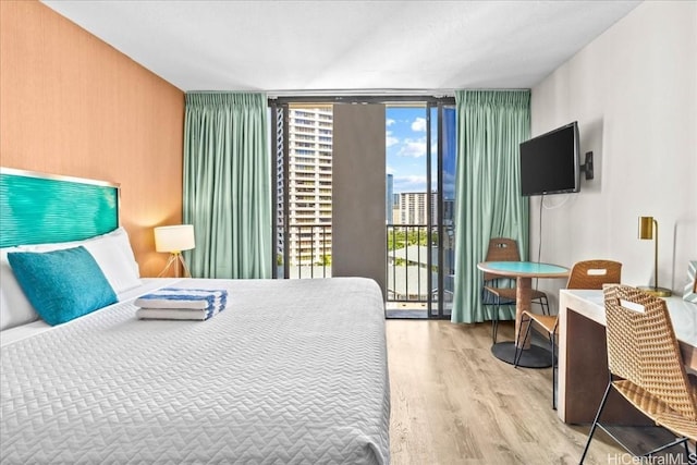 bedroom featuring access to exterior, a wall of windows, and wood finished floors