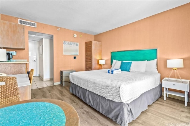 bedroom featuring light wood-type flooring, visible vents, and baseboards