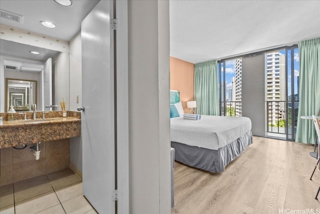 bedroom featuring expansive windows, multiple windows, wood finished floors, and visible vents