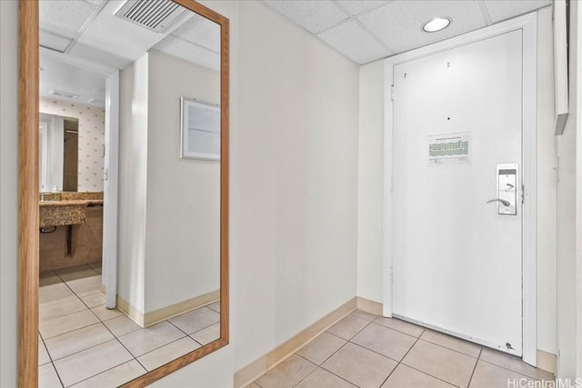 interior space featuring visible vents, light tile patterned flooring, a paneled ceiling, and baseboards