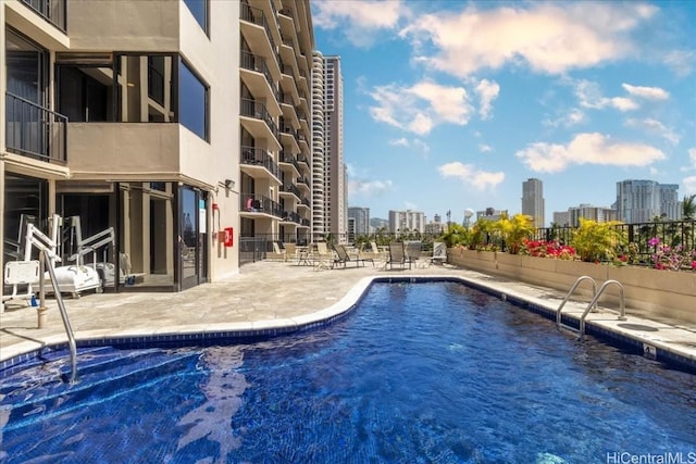 community pool featuring a view of city, a patio area, and fence