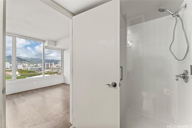 full bath with a stall shower, a city view, and wood finished floors