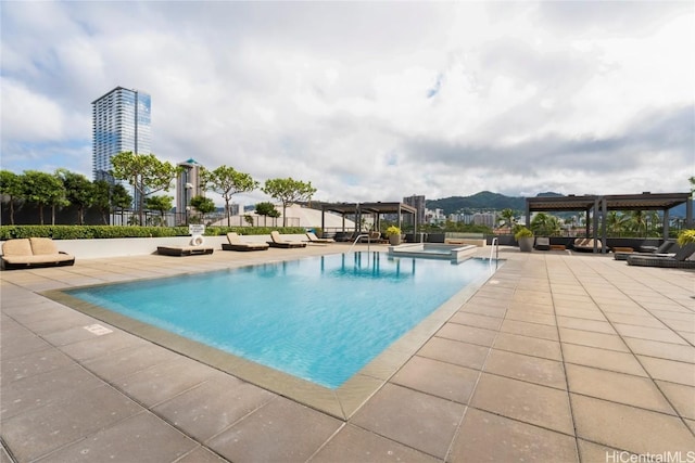 view of pool with a patio area, a pool with connected hot tub, and a pergola