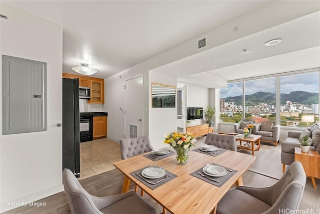 dining area featuring light wood finished floors, baseboards, electric panel, and visible vents