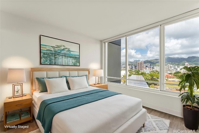 bedroom with a view of city, a mountain view, and wood finished floors