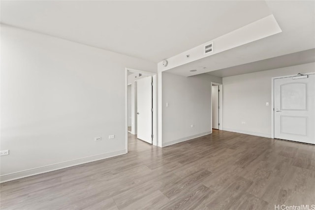 unfurnished room featuring light wood-style floors, visible vents, and baseboards