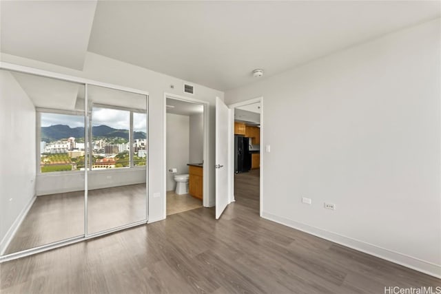 spare room with visible vents, dark wood-style flooring, a mountain view, and baseboards