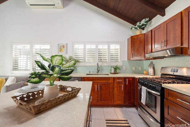 kitchen with backsplash, an AC wall unit, a sink, under cabinet range hood, and stainless steel gas range oven