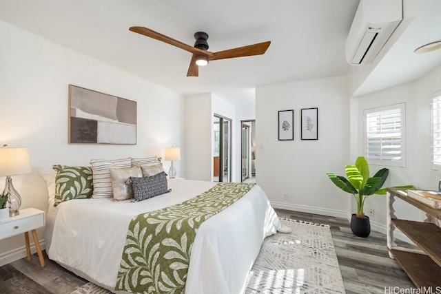 bedroom with connected bathroom, ceiling fan, wood finished floors, a wall mounted air conditioner, and baseboards