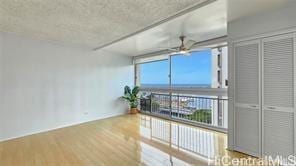 spare room with a wall of windows, wood finished floors, and a ceiling fan