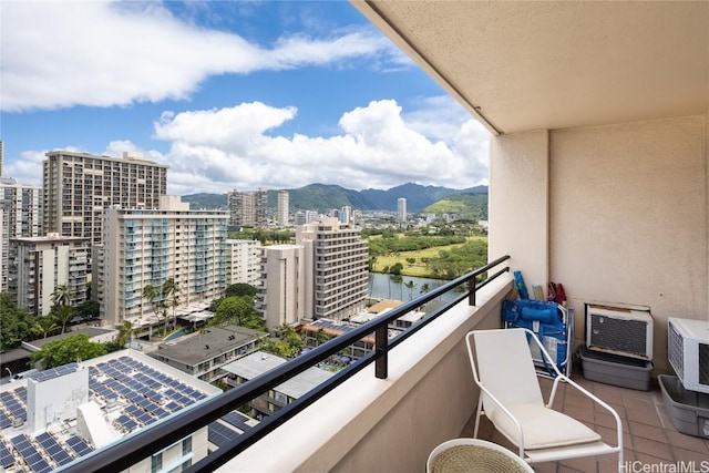 balcony with a water and mountain view, a city view, and an AC wall unit