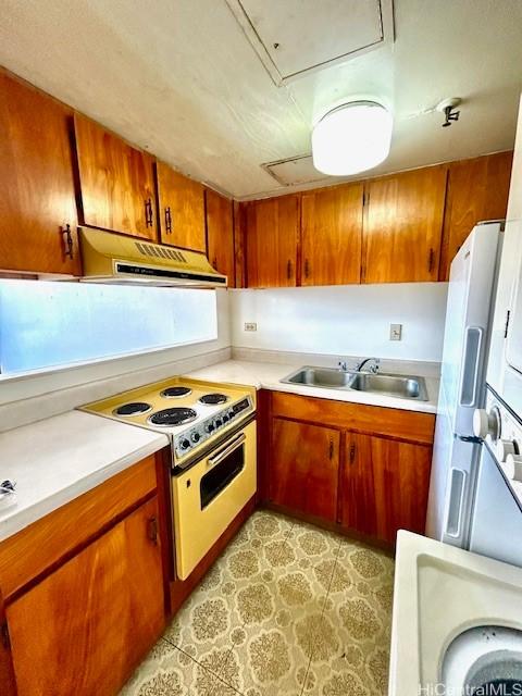 kitchen with white appliances, brown cabinets, light countertops, under cabinet range hood, and a sink