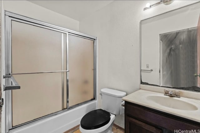 bathroom featuring toilet, shower / bath combination with glass door, and vanity