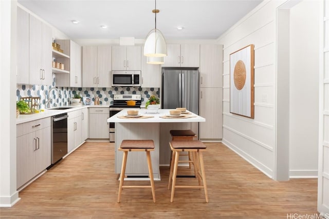 kitchen featuring a breakfast bar, stainless steel appliances, light countertops, open shelves, and a sink