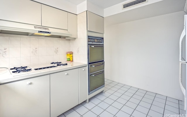 kitchen with under cabinet range hood, visible vents, light countertops, and black oven