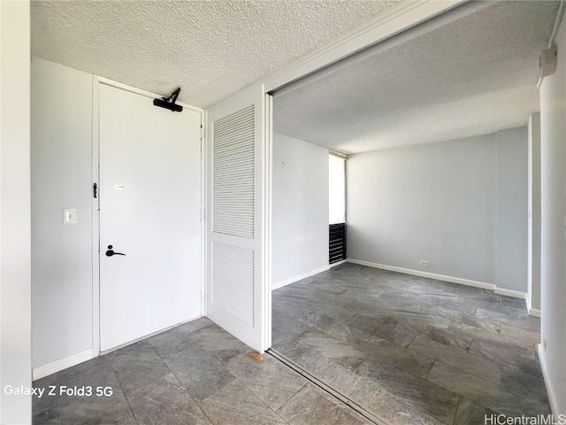 empty room featuring a textured ceiling and baseboards