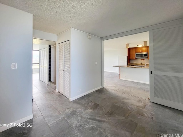 hallway featuring baseboards and a textured ceiling