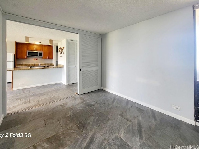 unfurnished living room featuring a textured ceiling and baseboards