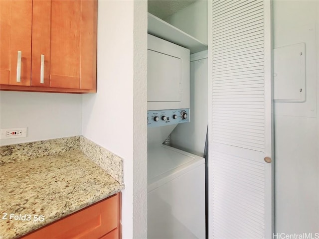 clothes washing area featuring stacked washer and dryer and laundry area