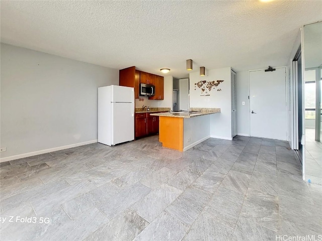 kitchen featuring stainless steel microwave, baseboards, open floor plan, a peninsula, and freestanding refrigerator