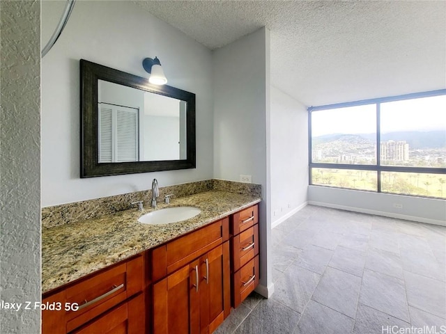 bathroom with a textured ceiling, vanity, and baseboards