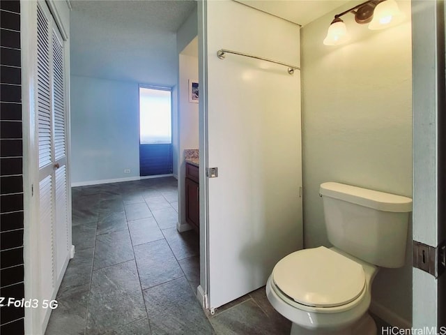 bathroom with vanity, toilet, and baseboards