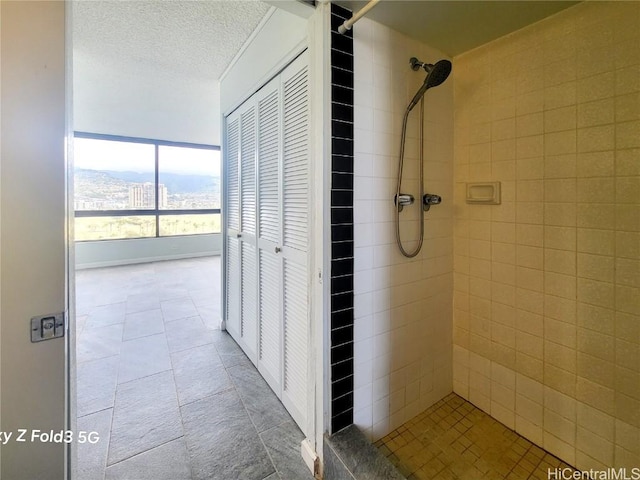 full bath with a closet, a textured ceiling, and a tile shower