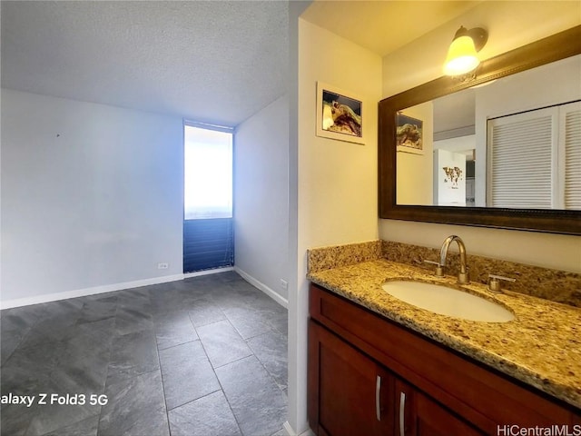 bathroom with tile patterned floors, baseboards, a textured ceiling, and vanity