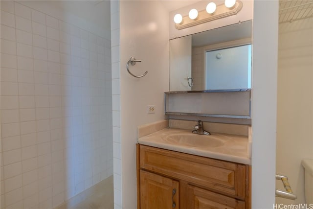 bathroom with tiled shower, toilet, and vanity