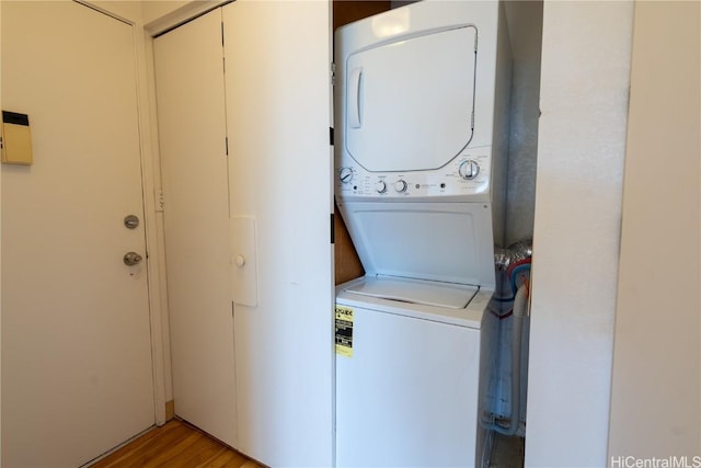 washroom featuring stacked washer / drying machine, light wood-style flooring, and laundry area