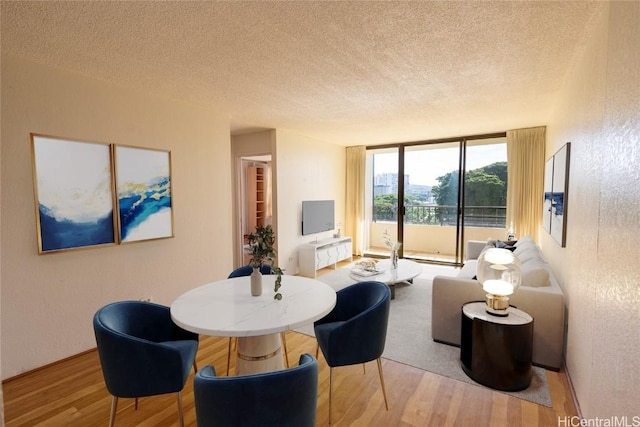 living area featuring a wall of windows, wood finished floors, a textured wall, and a textured ceiling