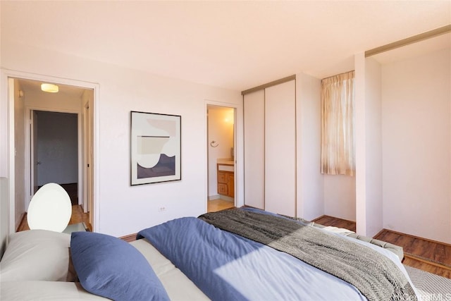 bedroom featuring a closet, connected bathroom, and wood finished floors