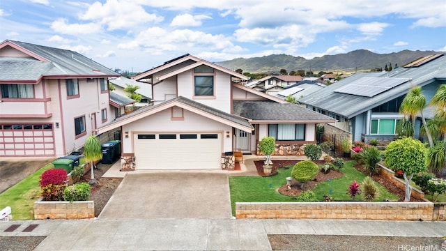 view of front of property featuring concrete driveway, an attached garage, a mountain view, and a front lawn